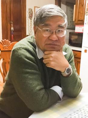 Portrait of a man sitting at a kitchen table.